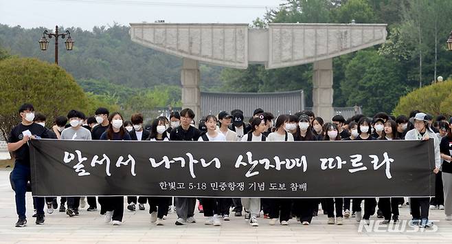 [광주=뉴시스] 김혜인 기자 = 5·18민주화운동 42주기를 닷새 앞둔 13일 오전 광주 북구 운정동 국립 5·18민주묘지에서 고등학생들이 추모 현수막을 든 채 묘역을 향햐고 있다.2022.05.13.hyein0342@newsis.com