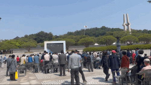 18일 오전 광주 북구 운정동 국립 5·18 민주묘지에서 열린 기념식 뒷편에 마련된 스크린 앞에서 시민들이 묵념하며 민주유공자를 기리고 있다. (사진=배진솔기자)