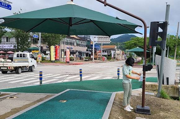 전라북도 순창군에 교차로에 설치된 무더위쉼터 그늘막을 군관계자가 점검하고 있다.[사진=순창군청]