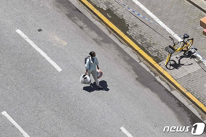 6일 (현지시간) 코로나19 봉쇄령이 내려진 중국 상하이의 텅 빈 도로에서 주민이 걸어가고 있다. © AFP=뉴스1 © News1 우동명 기자