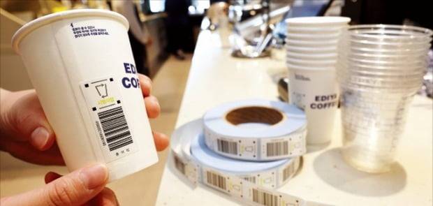 일회용 컵 보증금 제도 시행을 앞두고 서울의 한 프랜차이즈 커피숍 직원이 일회용 컵에 보증금 반환 코드를 부착하고 있다.  /연합뉴스