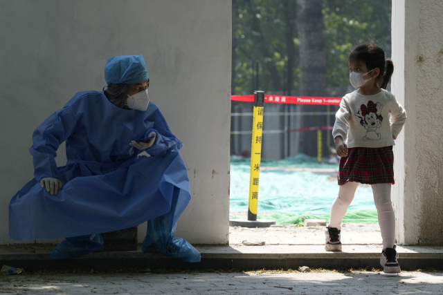 의료장비를 착용한 중국 의료인이 20일 베이징에서코로나19 검사를 받고 떠나는 아이를 바라보고 있다. AP=연합뉴스