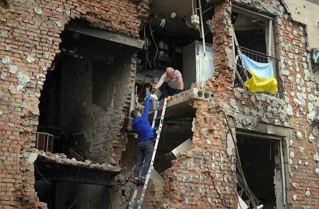 21일(현지시간) 우크라이나 키이우 인근 이르핀에서 발생한 러시아군의 포격으로 폐허가 된 집에서 주민들이 소지품을 꺼내고 있다. 이르핀｜AP연합뉴스