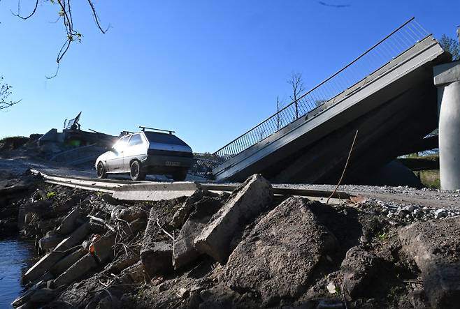 우크라이나 하르키우에서 파괴된 다리를 건너고 있는 한 차량. (사진=AFP)