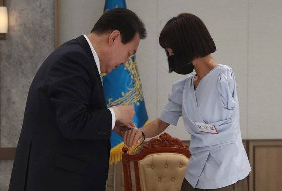 윤석열 대통령이 25일 용산집무실에서 취임식에 참석했던 국민대표 20인에게 대통령 기념시계를 선물하고 오찬을 함께 했다. 한팔 보디빌더로 WBC 피트니스 월드바디 클래식에서 4관왕을 차지한 김나윤씨에게 시계를 채워주고 있다. [대통령실사진기자단]