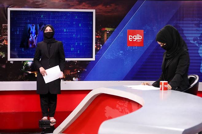 지난 22일(현지시간) 아프가니스탄 현지 방송 톨로뉴스의 여성 진행자인 소니아 니아치와 카티라 아흐메디가 얼굴을 가린 채 카메라 앞에 서 있다. 카불=로이터연합