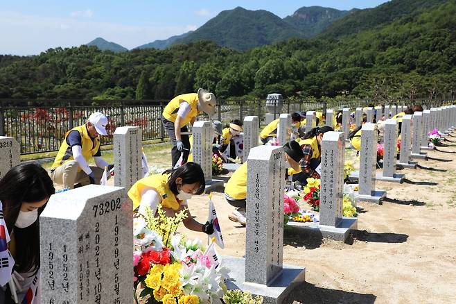 병무청 직원들이 26일 국립대전현충원에서 1사 1묘역 결연을 맺은 묘비에 태극기를 꽂고 있다.(병무청 제공)© 뉴스1