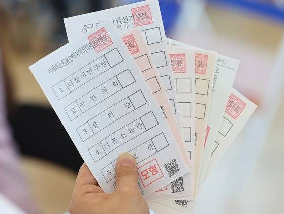 6·1 지방선거 사전투표를 하루 앞둔 26일 인천국제공항 제 1여객터미널에 설치된 사전투표소에서 관계자가 투표용지를 펼쳐 보이고 있다.   이번 선거에서 대부분의 유권자는 광역단체장(시·도지사), 교육감, 기초단체장(자치구·시·군의 장), 지역구 광역의원, 지역구 기초의원, 비례대표 광역의원, 비례대표 기초의원 등 총 7장의 투표용지를 받게 된다. 연합뉴스