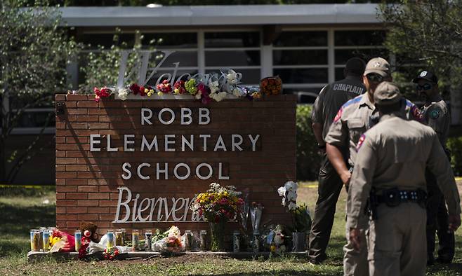 지난 25일(현지시간) 미국 텍사스주 소도시 유밸디의 롭 초등학교 앞 교명 표지판 주변에 총기난사 희생자들을 추모하는 꽃과 양초들이 놓여 있다.&nbsp;AP연합뉴스