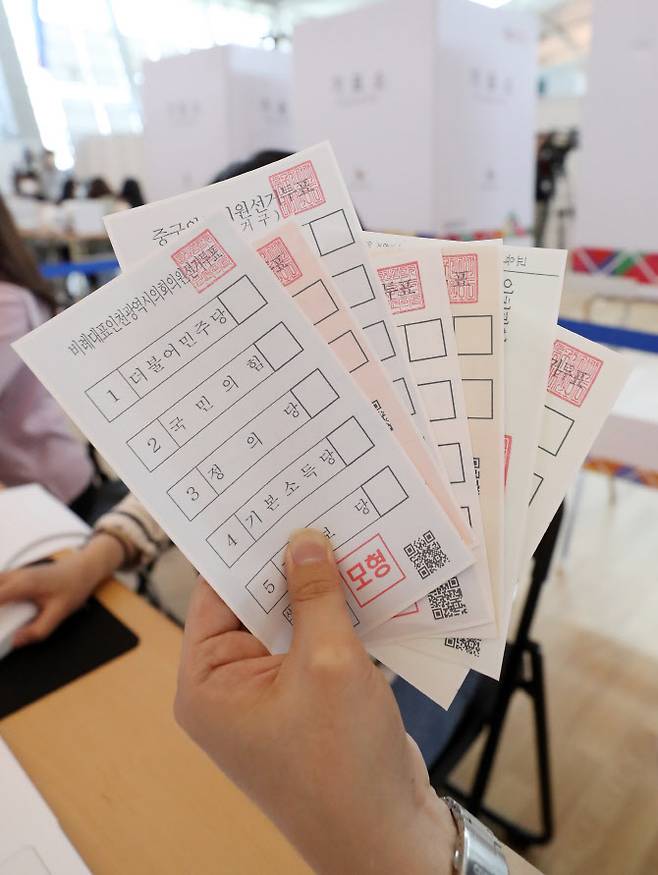 제8회 전국동시지방선거를 엿새 앞둔 26일 오후 인천국제공항 제1터미널에 마련된 사전투표소에서 관계자가 투표용지 모형을 취재진에 보여주고 있다.(사진=뉴스1)
