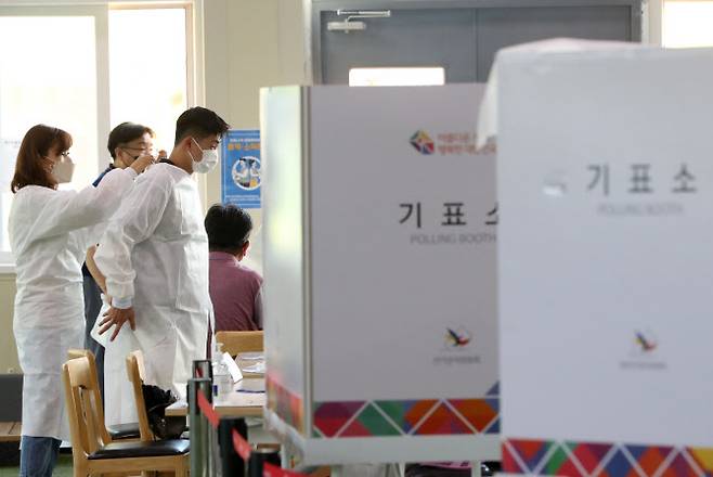 제8회 전국동시지방선거 사전투표 둘째 날인 28일 오후 강원 춘천시 신사우동 사전투표소가 마련된 춘천북부노인복지관에서 투표사무원들이 신종 코로나바이러스 감염증(코로나19) 확진자 투표 시작을 앞두고 보호복을 입고 있다.(사진=연합뉴스)