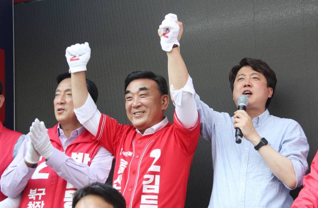 이준석 국민의힘 대표(오른쪽)가 22일 울산시 북구 명촌동에서 지방선거 지원 유세를 펼치며 김두겸 울산시장 후보(가운데)의 손을 치켜올리고 있다. / 연합뉴스