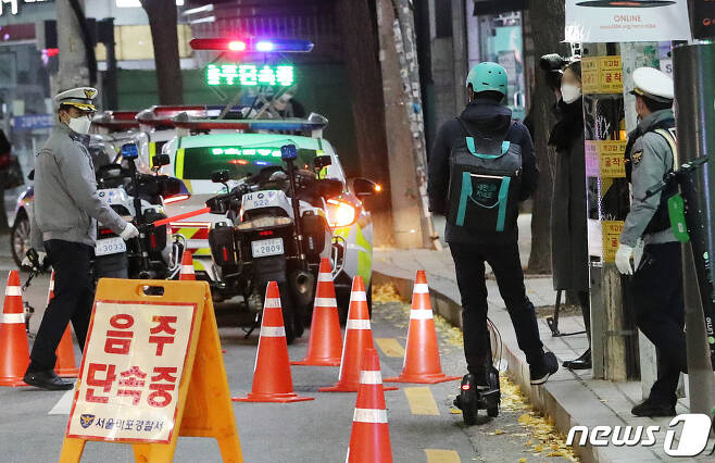 2020년 11월 27일 저녁 서울 마포구 서교동 일대에서 경찰들이 음주 단속을 실시하고 있는 가운데 전동킥보드로 차도를 달리던 배달원이 단속 구간을 그냥 지나치기 위해 인도(오른쪽)로 올라가려다 경찰에 제지당하고 있다. 해당 배달원은 음주상태는 아닌것으로 전해졌다. © News1 이성철 기자