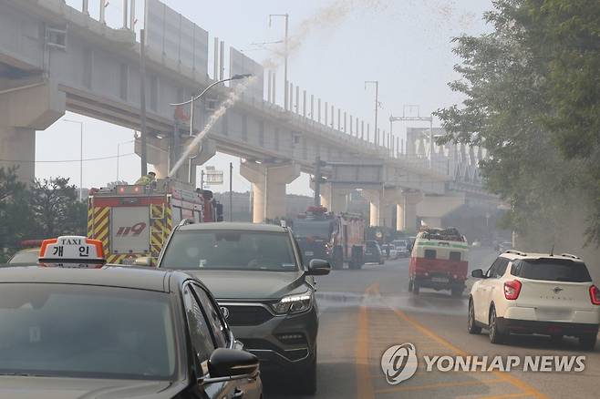 연기 자욱한 도로 (울진=연합뉴스) 손대성 기자 = 29일 오전 경북 울진군 근남면 일원에서 산불이 번지자 소방차가 물을 뿌려 불을 끄고 있다. 2022.5.29 sds123@yna.co.kr