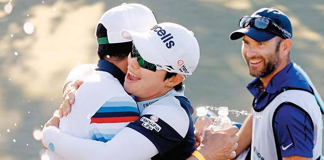 한국 선수들의 ‘맏언니’ 지은희(가운데)가 30일 미국 네바다주 라스베이거스에서 열린 LPGA 투어 뱅크 오브 호프 매치플레이에서 우승을 확정한 뒤 머리 위로 물을 끼얹으며 축하해준 팬 중 한 명과 포옹하고 있다. 그는 “단체 채팅방에서 해준 후배들의 응원이 큰 힘이 됐다”고 우승 소감을 밝혔다. /AFP 연합뉴스
