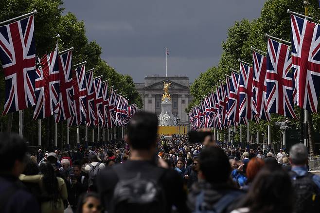 엘리자베스 2세 여왕 즉위 70년 기념행사를 맞아 영국 국기 유니언잭이 내걸린 런던 버킹엄궁 앞에서 사람들이 사진을 찍고 있다. AP 연합뉴스