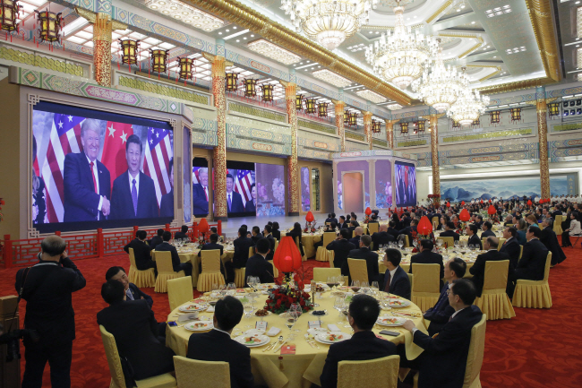 2017년 11월 중국 베이징 인민대회당에서 도널드 트럼프 당시 미국 대통령 방중을 기념하기 위해 열린 만찬에서 손님들이 트럼프 대통령과 시진핑 중국 국가주석의 회담 영상을 보고 있다. AP