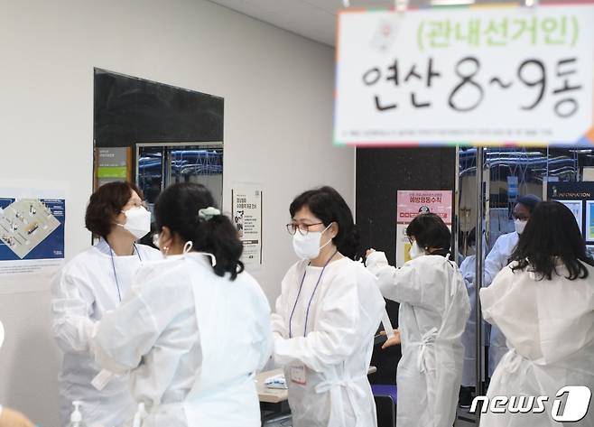 6·1 지방선거 사전투표 이튿날인 28일 부산 연제구 연산9동 행정복지센터에 마련된 사전투표소에서 신종 코로나바이러스 감염증(코로나19) 확진자 투표가 개시되기 30분 전 선거 사무원들이 방역복을 입고 있다.2022.5.28/© 뉴스1 노경민 기자