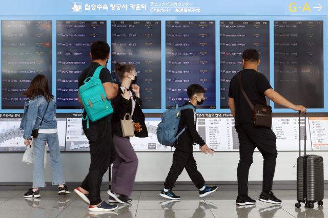 3일 인천국제공항 제1터미널에서 출국자들이 탑승 수속 정보가 담긴 전광판 앞을 지나고 있다. 연합뉴스