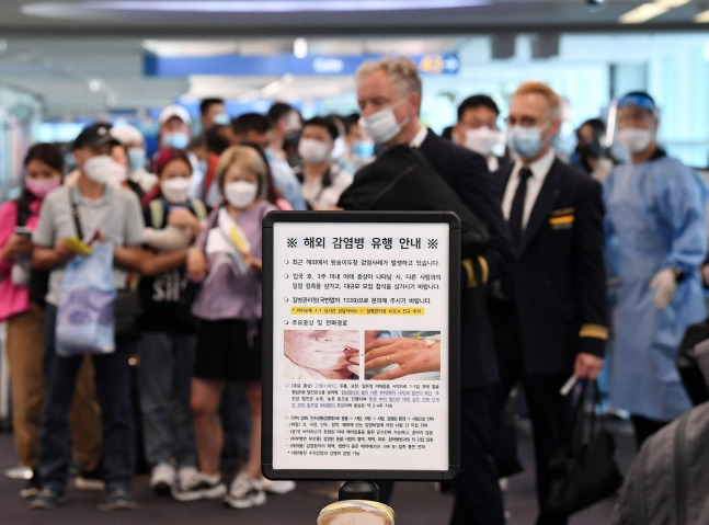 27일 오전 인천국제공항 제1터미널 입국장에 해외 입국자들이 검역을 받기 위해 대기하고 있다. 입국자들 앞에 원숭이두창 관련 안내문이 세워져 있다. 뉴스1