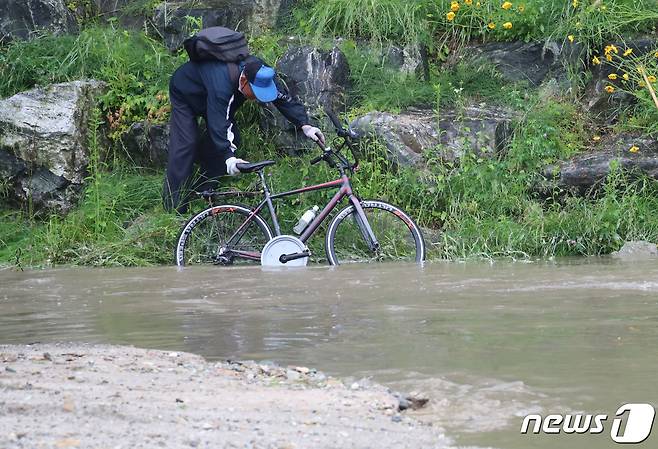 갑작스런 폭우로 산책로가 침수된 대전 유성구 유성천에서 자전거를 타던 시민이 몸을 피하고 있다.  © News1 김기태 기자