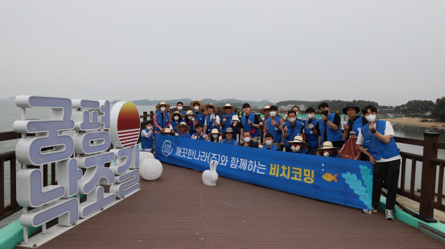 깨끗한나라 임직원이 자원봉사자들과 함께 22일 경기도 화성시 궁평항 해변에서 쓰레기와 어업 폐기물을 수거한 후 기념 촬영을 하고 있다. 사진 제공=깨끗한나라