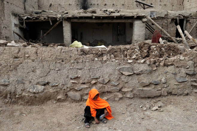 강진이 발생한 아프가니스탄 파크티카주 가이안에서 23일(현지시간) 한 소녀가 무너진 집 앞에 앉아 있다. | 로이터연합뉴스