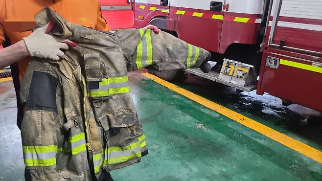 경기 화성시의 한 119안전센터에서 근무하는 소방관이 지난 24일 까맣게 변한 방화복을 들어 보이고 있다.