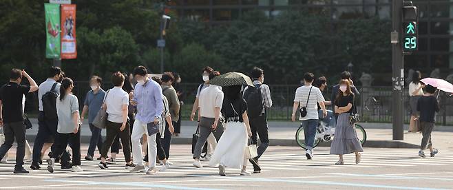 지난 21일 오전 서울 광화문역 인근에서 출근하는 시민들이 양산이나 손으로 햇빛을 가리며 길을 건너고 있다. /연합뉴스