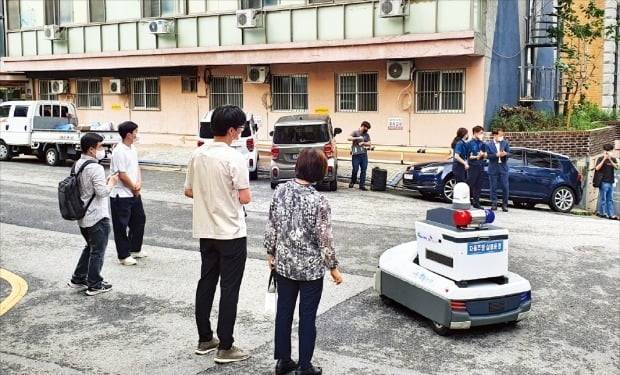 < 사람 없이 못 다니는 방범 로봇 > 지난 16일 서울 신림동 해태어린이공원 인근 골목길에서 관악구, 관악경찰서 등 관계자와 시민들이 지켜보는 가운데 자율주행 방범 로봇 ‘골리’가 모니터링 요원(왼쪽 세 번째)을 대동한 채 순찰을 하고 있다.  /박한신 기자