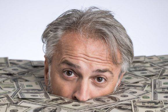 돈에 파묻힌 남자. 어떻게 부자가 됐느냐에 따라 빈곤층과 부의 재분배에 대한 시각도 달라진다. [사진=게티이미지뱅크]