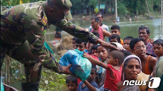 방글라데시에서 한 군인이 지난 25일 홍수 피해를 입은 주민들에게 음식을 나눠주고 있다 © 뉴스1