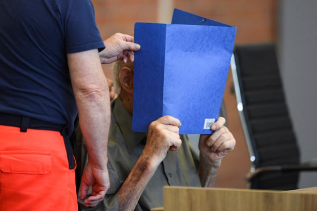독일 작센하우젠 강제수용소 내 유대인 학살에 가담한 101세 남성이 28일(현지시간) 브란덴부르크주 노이루핀 법원에서 열린 재판에 출석하러 가면서 얼굴을 가리고 있다. 노이루핀=로이터 연합뉴스