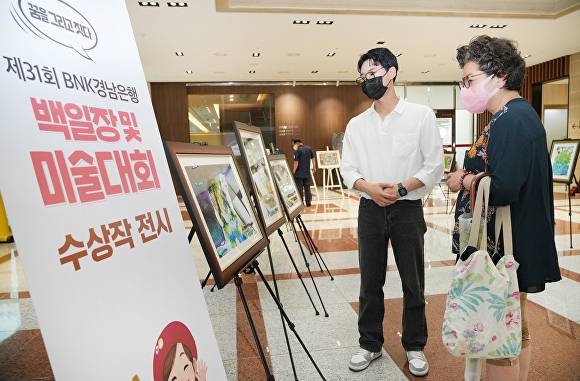 BNK경남은행 본점을 방문한 지역민들(사진)이 제31회 BNK경남은행 백일장과 미술대회 수상 작품을 관람하고 있다. [사진=BNK경남은행]