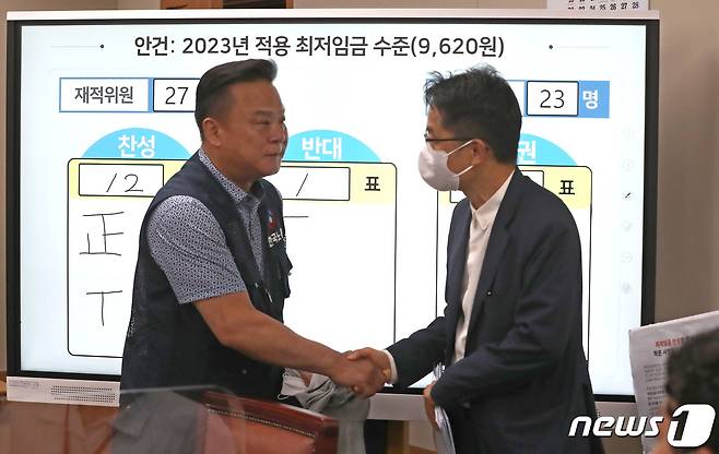 30일 새벽 정부세종청사 최저임금위원회 회의실에서 열린 제8차 전원회의에서 재적 27, 출석 23, 찬성12, 반대1, 기권 10으로 2023년 최저임금이 9천620원으로 결정되며 박준식 최저임금위원회 위원장과 한국노총 이동호 사무총장이 악수를 나누고 있다. 2022.6.29/뉴스1 © News1 김기남 기자