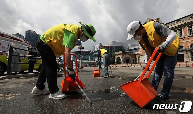 1일 서울 중구 서울역 광장에서 다시서기 자활사업단 관계자들이 신종 코로나바이러스 감염증(코로나19) 임시 선별검사소 컨테이너 등 시설물 철거를 마친 뒤 바닥에 남겨져있던 잔해 및 쓰레기 등을 줍고 있다. 2022.7.1/뉴스1 © News1 이동해 기자