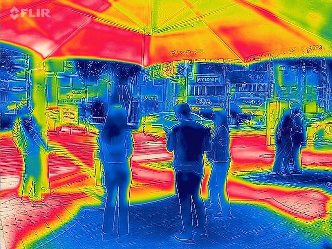 서울 한낮 기온이 34.2도까지 치솟은 3일 서울 중구 신당역 인근 건널목 그늘쉼터에서 더위를 피하는 시민들을 열화상 카메라로 촬영한 모습. 온도가 높은 부분은 붉게, 낮은 부분은 푸르게 나타난다. 연합뉴스