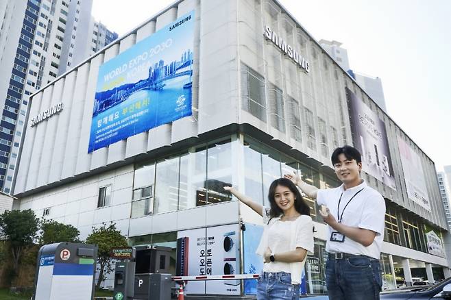 삼성전자가 7월 1일부터 부산 전역 23개 매장에서 '2030 부산세계박람회' 유치를 응원하는 광고를 선보였다. 삼성전자 모델들이 삼성 디지털프라자 해운대본점에서 '2030 부산엑스포' 유치를 응원하고 있다. /사진제공=삼성전자