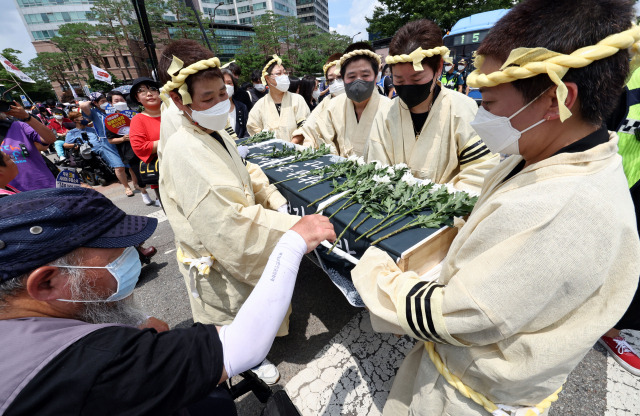 서울 용산구 삼각지역 인근에서 1일 열린 발달·중증장애인 참사 T4 장례식에서 상여행진 중 장애인 참석자들이 헌화를 하고 있다. /연합뉴스