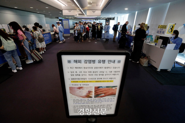 인천국제공항 제1터미널 입국장 승객들 앞에 원숭이두창 관련 안내문이 세워져 있다. 김창길기자