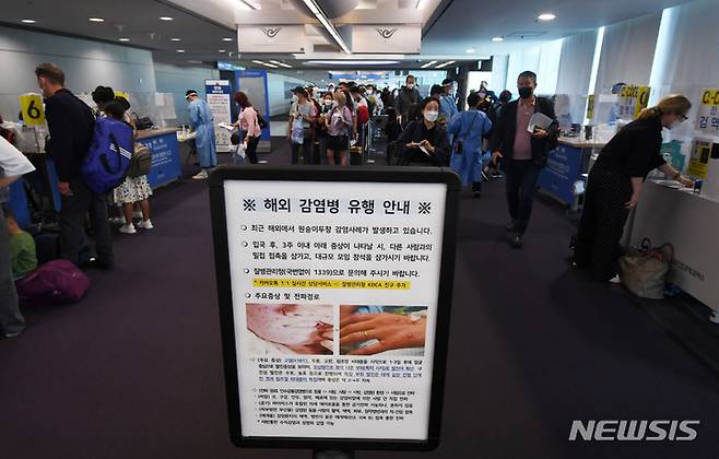 [인천공항=뉴시스] 지난 5월27일 오전 인천국제공항 제1여객터미널 입국장에서 독일 프랑크푸르트와 우즈베키스탄발 탑승객들이 검역을 받기 위해 대기하고 있는 가운데 원숭이 두창 안내문이 게시되어 있다. (공동취재사진) 2022.07.05. photo@newsis.com