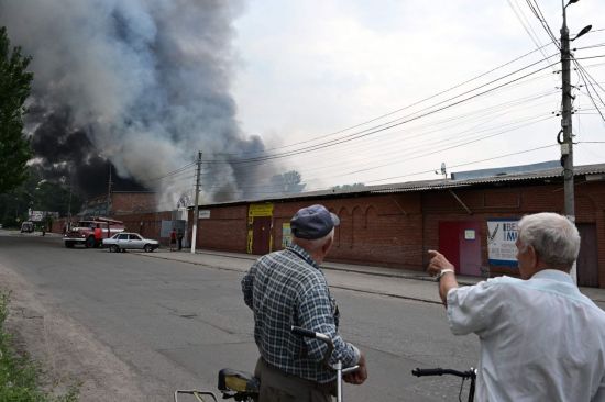 5일(현지시간) 우크라이나 크라마토스크 북쪽 슬로뱐스크에서 주민들이 러시아의 포격으로 연기가 피어오르는 중앙 시장을 지켜보고 있다. (사진 제공=AFP연합뉴스)