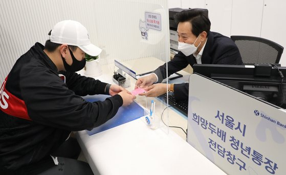 오세훈 서울시장이 신한은행 시청금융센터점에서 '희망두배 청년통장' 신규 개설자에게 통장을 전달하고 있다. [연합뉴스]