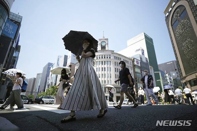 [도쿄=AP/뉴시스] 28일 일본 도쿄에서 강렬한 햇빛을 피하고자 양산 쓴 시민들이 건널목을 건너고 있다. 2022.06.28.