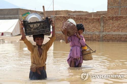 폭우로 물에 잠긴 파키스탄 퀘타에서 가재도구를 옮기는 어린이. [AFP 연합뉴스 자료사진. 재판매 및 DB 금지]