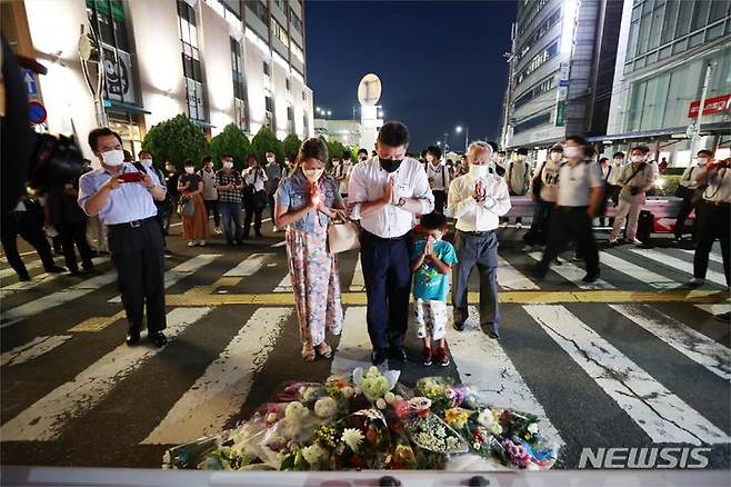 [나라(일본)=AP/뉴시스]지난 8일 밤 아베 신조 전 일본 총리가 총격을 당한 나라현의 현장에 마련된 임시 헌화대에 시민들이 추모를 위해 모여있다.  아베 전 총리는 8일 오전 나라시에서 가두 연설 중 총격을 받고 병원으로 이송됐으나 사망했다. 2022.07.09.