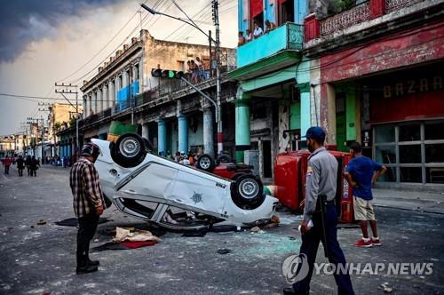 지난해 7월 11일 반정부 시위가 벌어진 쿠바 아바나 거리에 경찰 차량이 뒤집힌 채로 있다.
 [AFP=연합뉴스 자료사진. 재판매 및 DB 금지]