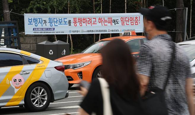 횡단보도 앞 일시정지 의무를 확대하는 등 보행자 보호를 강화한 개정 도로교통법 시행을 하루 앞둔 11일 오전 서울 종로구 경복궁역 교차로 횡단보도 주변에 안내 펼침막이 걸려 있다. 개정 도로교통법에 따라 운전자는 횡단보도를 건너려는 보행자가 서 있는 것이 보이기만 해도 일단 멈춰야 한다. 김정효 기자 hyopd@hani.co.kr