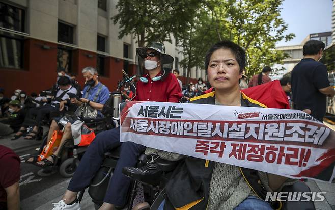 [서울=뉴시스] 장애인들의 탈시설을 지원하고 지역사회 정착을 돕기 위한 '서울특별시 장애인 탈시설 및 지역사회 정착 지원에 관한 조례(장애인 탈시설 조례)'가 공포됐다. 사진은 전국장애인차별철폐연대 관계자들이 지난달 21일 오후 서울 중구 서울시의회 앞에서 장애인 탈시설 조례 제정 촉구 집회를 하고 있다. (사진=뉴시스DB) photo@newsis.com