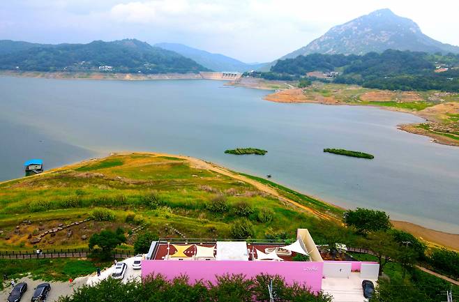 합천호 핑크카페와 반영이 드리워져 수중매(梅)가 될 주변 산들. 수중매를 보려면 호수 가까운 곳 데크길을 산책하면 된다. [투어기획 ‘지앤씨21’ 드론 촬영]